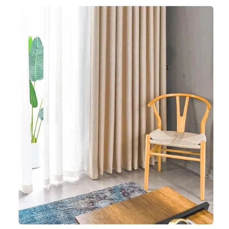 Chaise de style scandinave dans un salon moderne avec rideaux beiges, décor minimaliste et plante verte. Idéal pour une ambiance chaleureuse et accueillante.