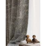 Rideau élégant gris à motif texturé, idéal pour une ambiance moderne dans le salon ou la chambre. Complété par des objets décoratifs en bois sur une étagère, ce rideau ajoute une touche contemporaine et chaleureuse à votre intérieur. Parfait pour tamiser la lumière et apporter une touche de sophistication à votre décoration d'intérieur.