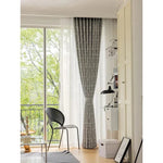 Rideau gris moderne et élégant installé dans un salon lumineux avec vue sur un balcon verdoyant. Ambiance cosy et contemporaine, idéale pour embellir votre intérieur tout en filtrant la lumière naturelle. Accessoire décoratif parfait pour une décoration intérieure raffinée.