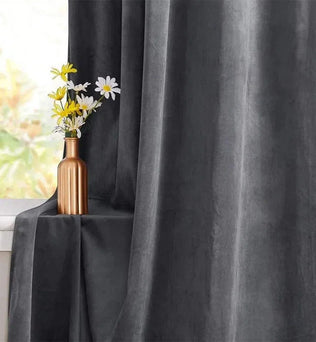 Rideau gris élégant installé près d'une fenêtre, avec un vase doré contenant un bouquet de fleurs blanches et jaunes. Accessoire de décoration intérieure sophistiqué pour un salon moderne. Rideau occultant idéal pour réguler la lumière naturelle et ajouter une touche de style contemporain.