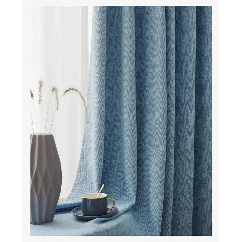 Rideau bleu élégant pour salon avec motif décoratif, accompagné d'une tasse design sur une table près d'une fenêtre, complétant un intérieur moderne sophistiqué. Vase décoratif en arrière-plan pour une touche artistique. Idéal pour apporter élégance et style à votre espace de vie.