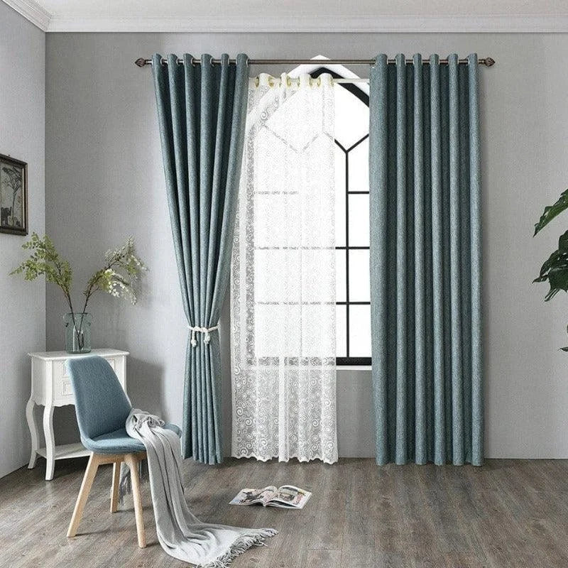 Rideau élégant pour salon moderne, couleur bleue, s'harmonisant avec une décoration intérieure contemporaine. Fenêtre encadrée par des voilages délicats, ajoutant une touche de sophistication. Sol en bois accentuant l'ambiance chaleureuse de la pièce. Accessoires assortis incluant chaise et table pour un ensemble harmonieux. Idéal pour embellir et personnaliser votre espace de vie.