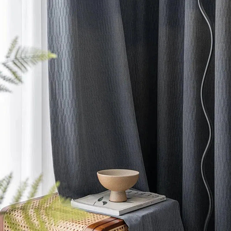 Rideaux élégants et modernes de couleur sombre, parfaits pour créer une ambiance sophistiquée et accueillante dans votre salon ou chambre. Idéal pour une décoration intérieure chic et contemporaine. Accessoirisé avec des éléments décoratifs comme un bol minimaliste sur une table aux lignes épurées.