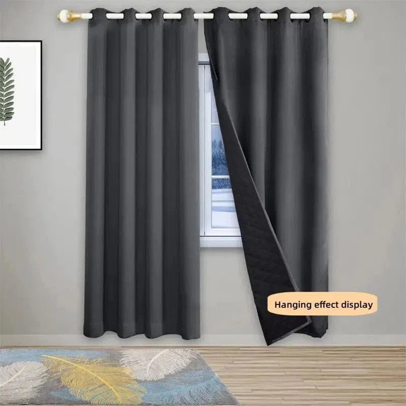 Rideau occultant gris élégant avec œillets, installé dans un salon moderne. Décor intérieur avec tableau de feuille verte et tapis coloré, optimisant l'isolation thermique et l'obscurité de la pièce. Idéal pour une décoration contemporaine et fonctionnelle.