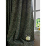 Rideau épais gris foncé drapé dans un intérieur lumineux, accentuant l'élégance d'une pièce. Accessoire déco avec bougie dans son support en verre, créant une ambiance chaleureuse près de la fenêtre ouverte avec vue sur un paysage verdoyant. Idéal pour ajouter une touche sophistiquée à votre salon ou chambre.