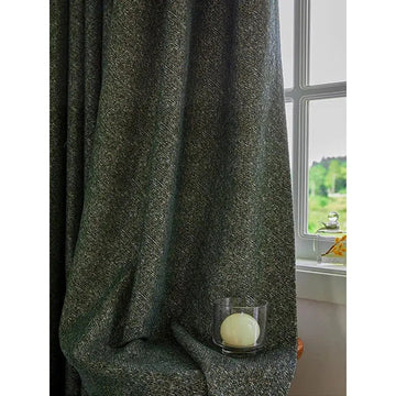 Rideau épais gris foncé drapé dans un intérieur lumineux, accentuant l'élégance d'une pièce. Accessoire déco avec bougie dans son support en verre, créant une ambiance chaleureuse près de la fenêtre ouverte avec vue sur un paysage verdoyant. Idéal pour ajouter une touche sophistiquée à votre salon ou chambre.
