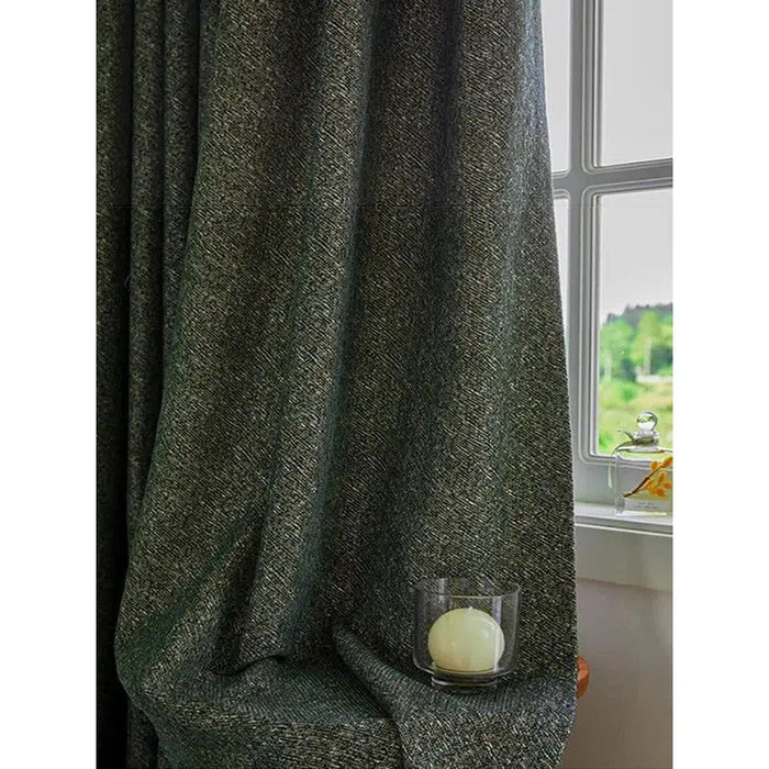 Rideau épais gris foncé drapé dans un intérieur lumineux, accentuant l'élégance d'une pièce. Accessoire déco avec bougie dans son support en verre, créant une ambiance chaleureuse près de la fenêtre ouverte avec vue sur un paysage verdoyant. Idéal pour ajouter une touche sophistiquée à votre salon ou chambre.