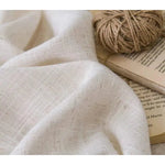 Image d'un tissu blanc doux accompagné d'une pelote de fil, idéal pour des projets de couture ou de décoration intérieure. Le tissu est posé sur un livre, mettant en valeur son élégance et sa versatilité pour l'artisanat et le design. Accessoire parfait pour des créations faites à la main.