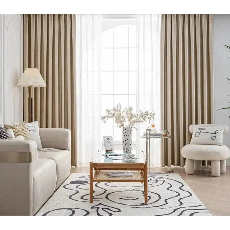 Salon moderne avec des rideaux élégants, décoré avec goût pour un intérieur chaleureux, comprenant un canapé confortable, une table basse en bois, et un tapis design. Parfait pour créer une ambiance accueillante et sophistiquée dans votre maison. Idéal pour ceux qui recherchent un agencement harmonieux et chic.