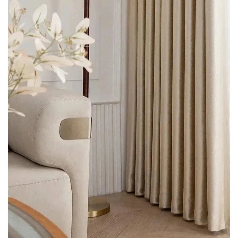 Canapé beige élégant avec accoudoirs métalliques modernes, associé à des rideaux assortis pour un salon raffiné et lumineux. Parfait pour une décoration intérieure contemporaine, mettant en valeur une ambiance chaleureuse et accueillante.