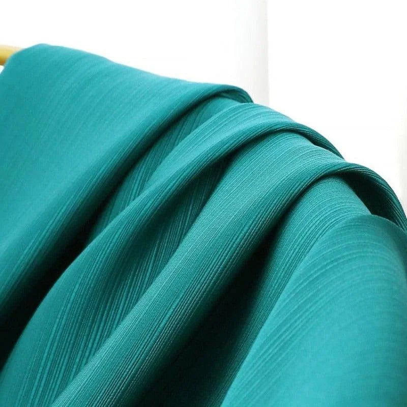 Image montrant un élégant tissu vert turquoise avec des plis subtils, idéal pour la confection de vêtements modernes et accessoires de décoration intérieure. Parfait pour ajouter une touche de couleur vibrante à tout projet créatif.