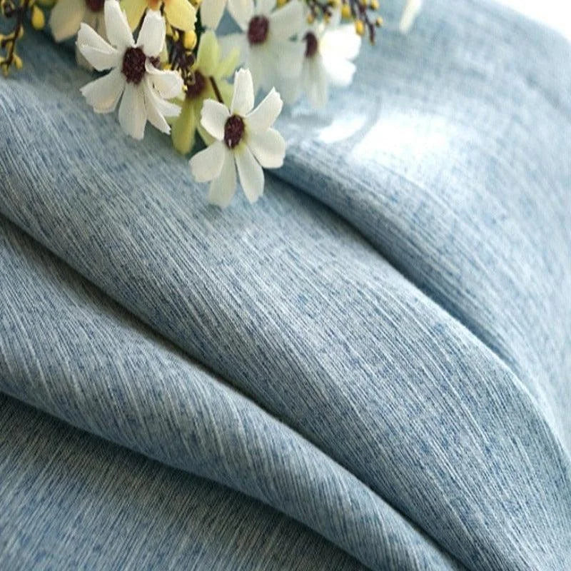 Textile élégant couleur bleu clair drapé délicatement, décoré de fleurs blanches. Parfait pour des créations de mode, ajoutant une touche de sophistication et de fraîcheur à toute réalisation. Idéal pour les tendances printemps-été et les projets de couture contemporains.