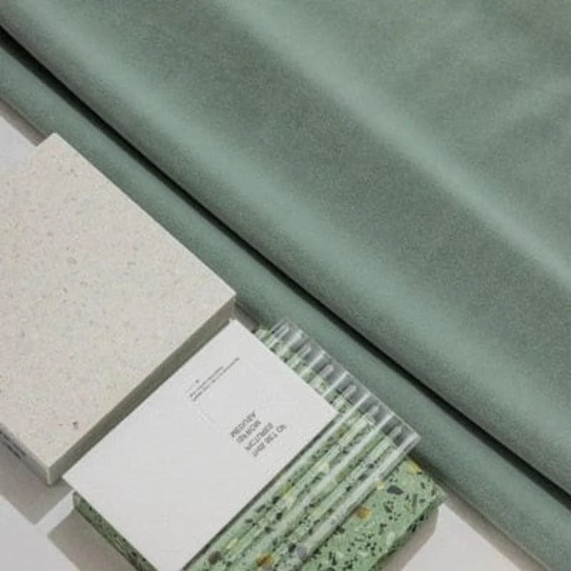 Echantillons de couleurs pour aménagement intérieur, montrant un textile vert doux et divers matériaux décoratifs, idéal pour inspirer des projets de design et décoration d'intérieur contemporains.