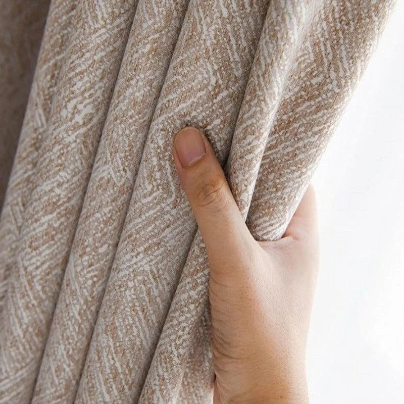 Main tenant un rideau beige texturé, ajoutant une touche élégante et naturelle à votre intérieur. Solution idéale pour un ameublement raffiné et moderne, offrant intimité et style à votre décoration intérieure.