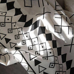 Tissu décoratif avec motifs géométriques noirs sur fond blanc, idéal pour ajouter une touche moderne à votre intérieur. Ce design unique combine des formes abstraites, parfait pour un salon contemporain ou une chambre tendance. Personnalisez votre espace avec cet élément décoratif chic.
