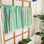 Rideau coloré à motifs zigzag installée dans une décoration intérieure moderne, parfaite pour ajouter une touche vibrante et élégante à votre espace. Ces rideaux uniques disposent d'un design multicolore, intégrant des teintes vertes, orange et bleues, idéal pour illuminer une pièce. Complément idéal pour un aménagement intérieur tendance.