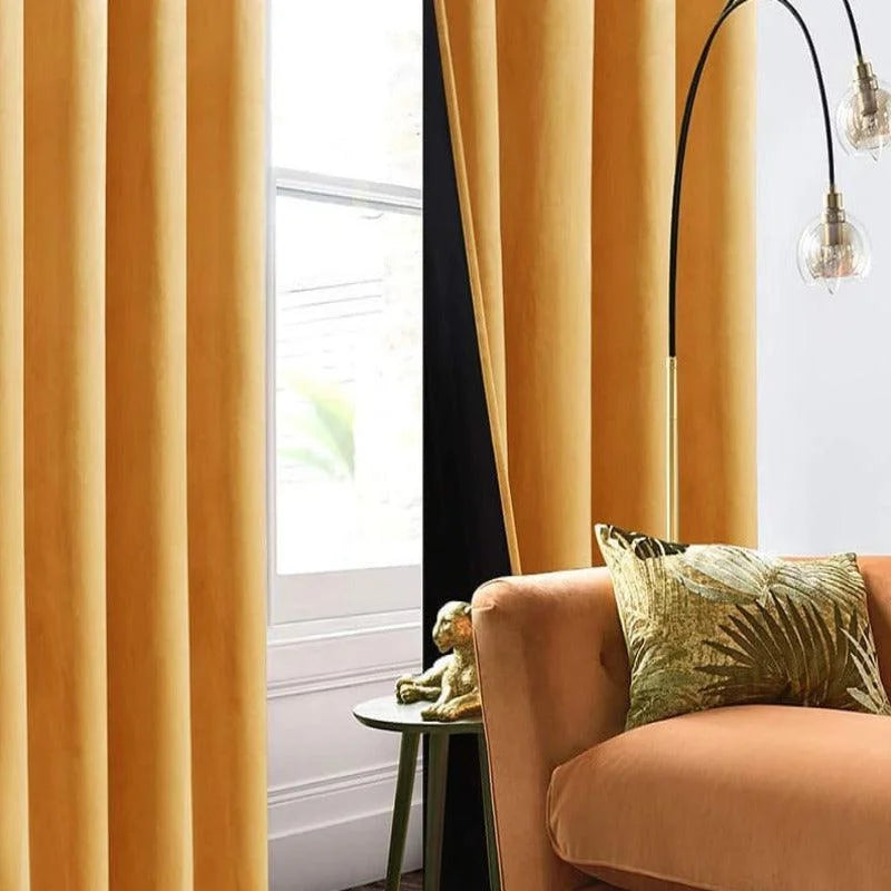 Rideaux élégants de couleur jaune doré dans un salon moderne, créant une ambiance chaleureuse. Complètement intégrés à la décoration intérieure, ils s'harmonisent avec un canapé couleur terre cuite et un coussin à motif végétal. Une lampe d'appoint et une petite table décorative ajoutent une touche contemporaine. Idéal pour apporter luminosité et style à votre espace de vie.