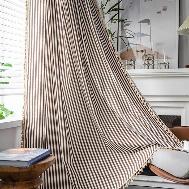 Rideau à rayures marron et blanc suspendu près d'une fenêtre, créant une ambiance chaleureuse et élégante dans un salon moderne avec des éléments décoratifs naturels.