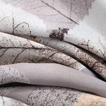 Gros plan sur un tissu imprimé avec des motifs de feuilles, mélange subtil de teintes naturelles marron et crème. Design élégant et moderne, idéal pour créer une ambiance chaleureuse et sophistiquée dans une décoration intérieure. Parfait pour le linge de maison ou les projets de décoration.