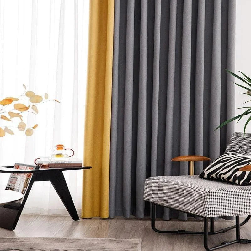 Rideaux modernes bicolores gris et jaune dans un salon élégant, complétant un intérieur chic avec un fauteuil confortable, une table basse design et une décoration délicate. Ambiance lumineuse et contemporaine pour un espace de vie harmonieux.