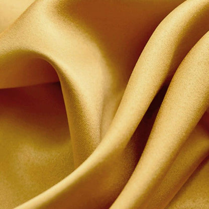 Texture fluide de tissu doré brillant, mettant en valeur un effet lumineux et élégant pour ajouter une touche de luxe à tout intérieur ou vêtement. Idéal pour la décoration ou la mode, ce textile ondulé offre une sensation visuelle de douceur et de raffinement.