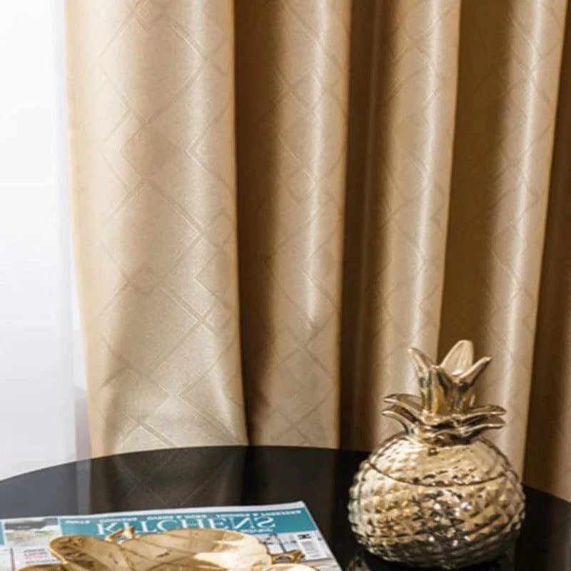 Rideau élégant beige avec motifs géométriques suspendu derrière une table noire. Un objet décoratif en forme d'ananas doré est posé sur la table, à côté d'un magazine. Ambiance raffinée et moderne pour un intérieur chic.