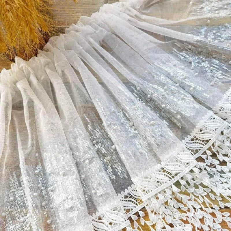 Voilage décoratif blanc avec sequins scintillants et bordure en dentelle, idéal pour habiller vos fenêtres avec élégance et sophistication. Parfait pour ajouter une touche de brillance à votre intérieur, tout en préservant la luminosité de votre pièce. Convient aux salons et chambres.