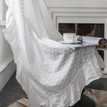 Textile d'intérieur blanc élégant avec motifs brodés, offert sur un fauteuil près d'une fenêtre, pour une ambiance de détente. Parfait pour créer un coin lecture confortable avec une touche décorative raffinée, accompagné d'une tasse de café et d'un magazine ouvert. Idéal pour ajouter une touche de luminosité et d'élégance à votre salon ou chambre.