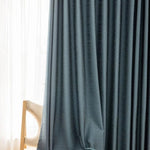Rideau occultant moderne bleu foncé suspendu dans un salon élégant, offrant une ambiance chaleureuse et intime. Parfait pour ajouter une touche de sophistication à votre décoration intérieure. Accessoire idéal pour le salon ou la chambre à coucher.
