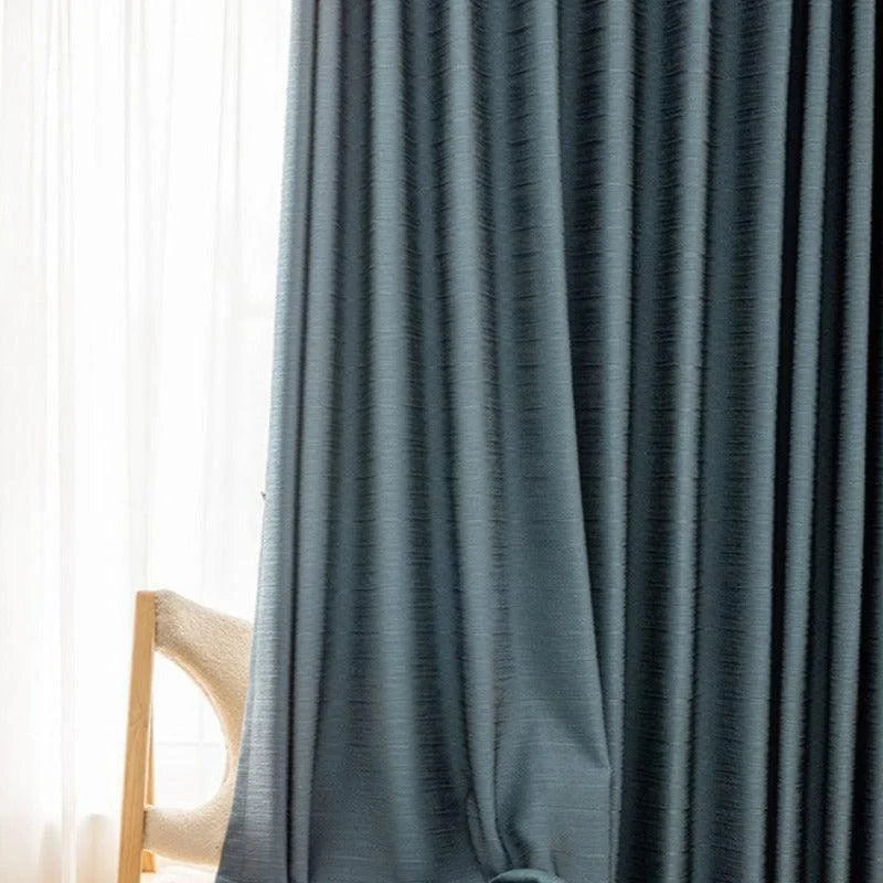 Rideau occultant moderne bleu foncé suspendu dans un salon élégant, offrant une ambiance chaleureuse et intime. Parfait pour ajouter une touche de sophistication à votre décoration intérieure. Accessoire idéal pour le salon ou la chambre à coucher.
