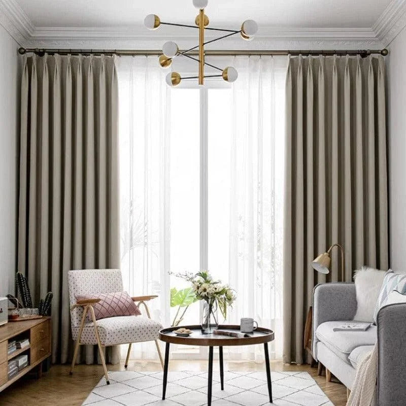 Salon moderne avec rideaux élégants, fauteuil confortable, canapé douillet, et table basse design, éclairé par un lustre contemporain. Ambiance chaleureuse et lumineuse, idéale pour la détente ou les moments conviviaux. Décoration intérieure raffinée avec des éléments de style scandinave et moderne.