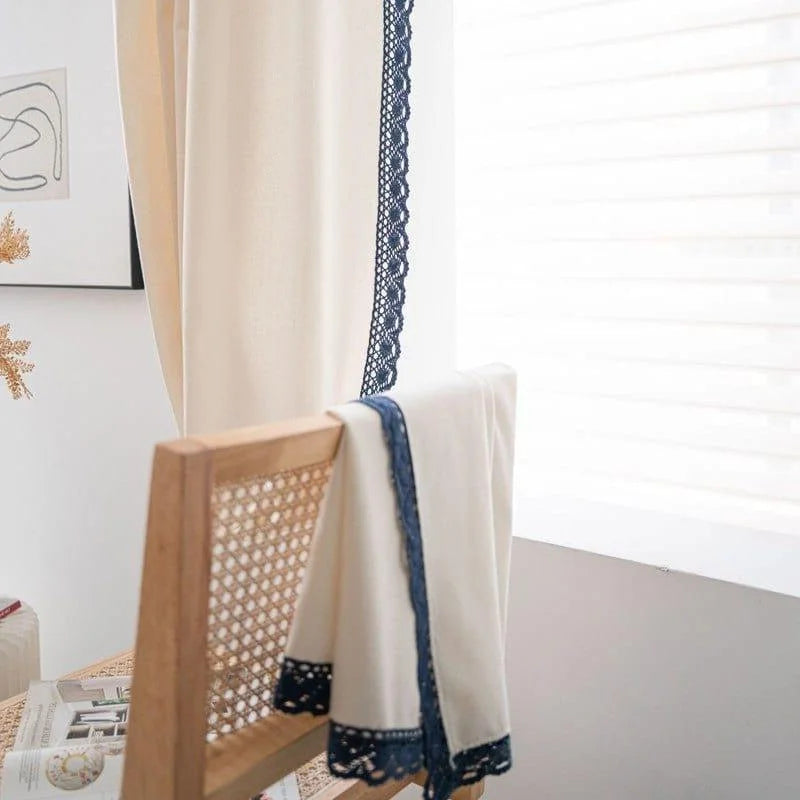Rideau décoratif élégant avec détails en dentelle bleue, accroché devant une fenêtre lumineuse. Design moderne pour un intérieur raffiné, idéal pour ajouter une touche de sophistication à votre salon ou chambre. Parfait pour filtrer la lumière tout en apportant une ambiance chaleureuse à vos espaces de vie.
