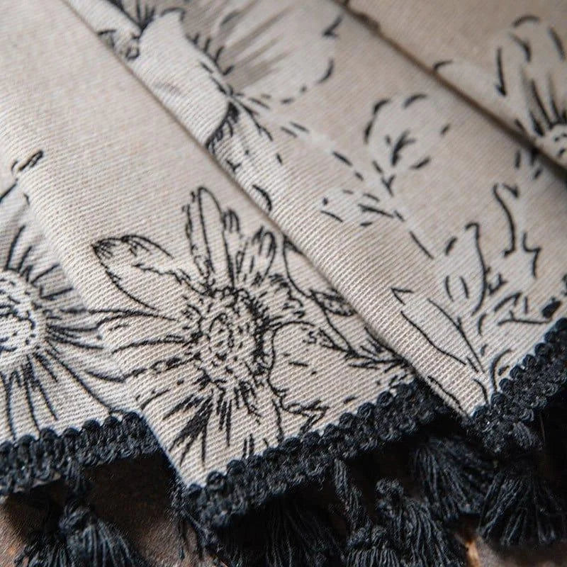 Élégant tissu décoratif à motifs floraux avec franges noires, idéal pour ajouter une touche sophistiquée à votre intérieur. Ce modèle raffiné convient parfaitement pour des rideaux, nappes ou autres projets de décoration.