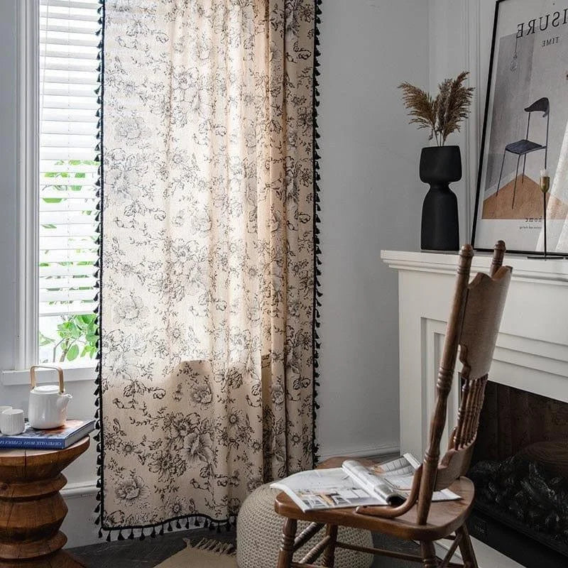 Rideau élégant à motif floral accroché devant une fenêtre, ajoutant une touche de charme et de lumière naturelle à une pièce décorée dans un style moderne. Ce rideau offre une esthétique raffinée et une ambiance chaleureuse, parfait pour les salons ou chambres à coucher. Les bordures ornées ajoutent une sophistication supplémentaire, faisant de cet accessoire un choix idéal pour embellir votre intérieur.