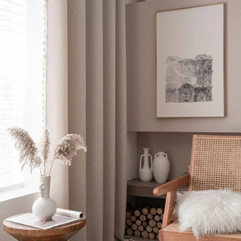 Fauteuil design en rotin et coussin moelleux dans un salon moderne et épuré. Décoration élégante avec vase de fleurs séchées et tableau artistique. Atmosphère chaleureuse et accueillante, idéale pour un espace détente. Fenêtre lumineuse et bibliothèque minimaliste en arrière-plan.