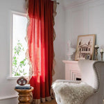 Rideau rouge élégant bordé de volants décoratifs transformant un salon sophistiqué, parfait pour ajouter une touche de chaleur et de couleur à votre espace intérieur. Ce rideau complète harmonieusement une décoration raffinée avec des éléments classiques comme un fauteuil confortable et un décor artistique. Parfait pour un aménagement intérieur chic et accueillant.