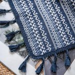 Tapis de table élégant avec motifs géométriques bleus et blancs, agrémenté de franges en forme de pompons, idéal pour ajouter une touche décorative à votre intérieur. Parfait pour une ambiance bohème et moderne.