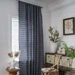 Rideau élégant avec motifs géométriques sombres, parfait pour embellir votre salon ou chambre. Ajoute une touche de sophistication et d'intimité à votre espace tout en s'harmonisant avec différents styles de décoration intérieure. Cadre moderne avec accessoires décoratifs et mobilier en bois pour une ambiance chaleureuse et accueillante.