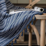 Tissu décoratif bleu et blanc avec motifs géométriques inspirés du design ethnique, idéal pour ajouter une touche de style traditionnel à votre intérieur. Plaid élégant disposé sur une chaise en bois, parfait pour une ambiance cosy et chaleureuse. Accessoire polyvalent pour personnaliser votre espace de vie.