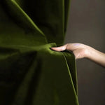 Image d'une main ajustant un rideau vert, capturant l'essence d'une décoration intérieure élégante et moderne, idéale pour sublimer votre espace de vie tout en ajoutant une touche de sophistication et de couleur.