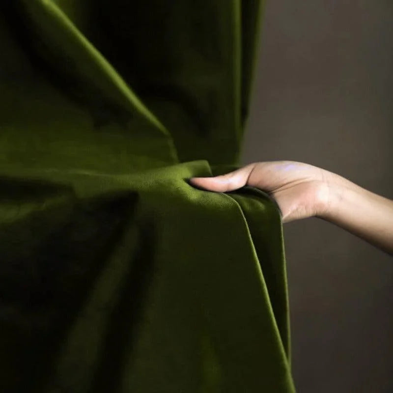 Image d'une main ajustant un rideau vert, capturant l'essence d'une décoration intérieure élégante et moderne, idéale pour sublimer votre espace de vie tout en ajoutant une touche de sophistication et de couleur.