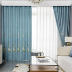 Rideaux élégants et modernes de couleur bleue avec motifs floraux pour salon. Décoration intérieure chic avec table basse en verre et canapé confortable. Ambiance lumineuse et harmonieuse idéale pour un style contemporain.