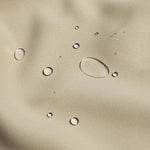 Gros plan d'une surface beige avec des gouttes d'eau illustrant les propriétés hydrofuges du produit, idéal pour protéger contre l'humidité et les éclaboussures.