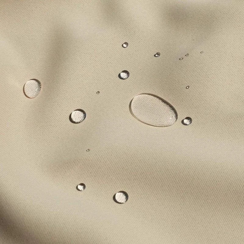 Gros plan d'une surface beige avec des gouttes d'eau illustrant les propriétés hydrofuges du produit, idéal pour protéger contre l'humidité et les éclaboussures.