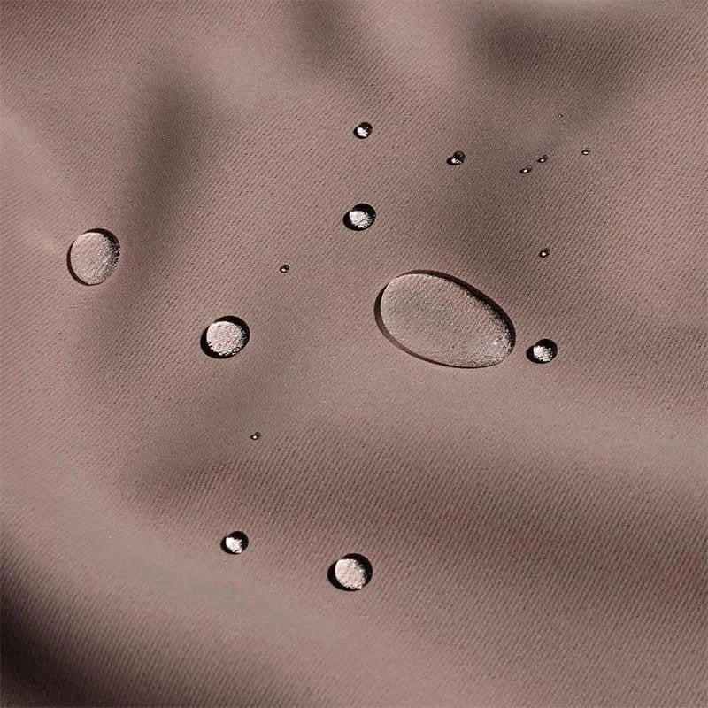 Gouttes d'eau sur surface imperméable, démontrant l'efficacité de la protection contre l'humidité. Idéal pour activités extérieures et conditions météorologiques variées. Fabrication soignée garantissant durabilité et performance optimale.