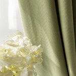 Rideau vert élégant avec motifs en chevrons, idéal pour ajouter une touche de sophistication à votre décoration intérieure. Parfait pour salon ou chambre, ce rideau offre une ambiance apaisante et se marie harmonieusement avec un bouquet de fleurs blanches pour un intérieur lumineux et accueillant.
