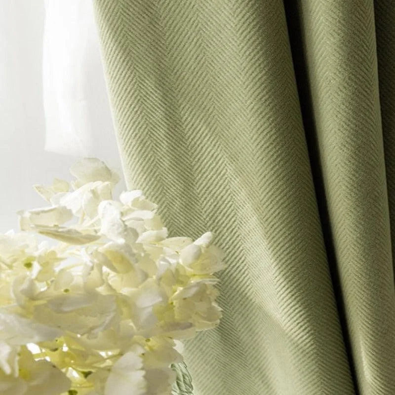 Rideau vert élégant avec motifs en chevrons, idéal pour ajouter une touche de sophistication à votre décoration intérieure. Parfait pour salon ou chambre, ce rideau offre une ambiance apaisante et se marie harmonieusement avec un bouquet de fleurs blanches pour un intérieur lumineux et accueillant.