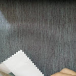 Tissu gris pour ameublement, échantillon sur fond ligneux. Parfait pour rideaux modernes ou revêtements de canapé, apporte une touche élégante à tout intérieur.