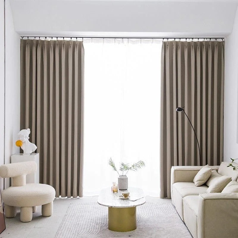 Salon moderne avec rideaux élégants et canapé confortable, accompagné d'une table basse design et d'un fauteuil contemporain. Décoration minimaliste et lumineuse, parfaite pour un intérieur chic et apaisant.