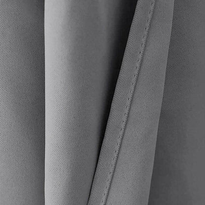 Gros plan sur un rideau gris, présentant des plis élégants et une couture fine. Ce rideau apportera une touche contemporaine à votre décoration intérieure, idéal pour créer une ambiance moderne et épurée. Parfait pour les salons, chambres ou bureaux, ajoutant une touche de sophistication minimaliste.